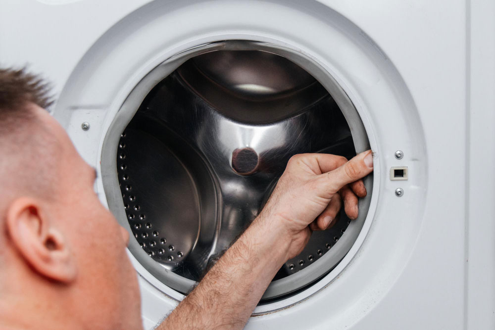 Techniker drückt mit seinem Daumen in die Dichtung eines Wäschetrockners